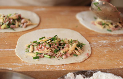 Three rolled-up dough circles stuffed with cheese, ham and greens on a wooden board sprinkled . 