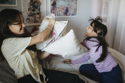 Happy sisters having pillow fight at home