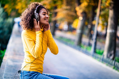 Happy young woman enjoying music in park