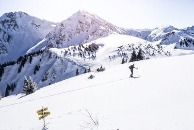 Mature man skiing on snow covered mountain against sky during sunny day