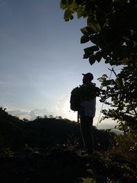 Rear view of man standing on field against sky