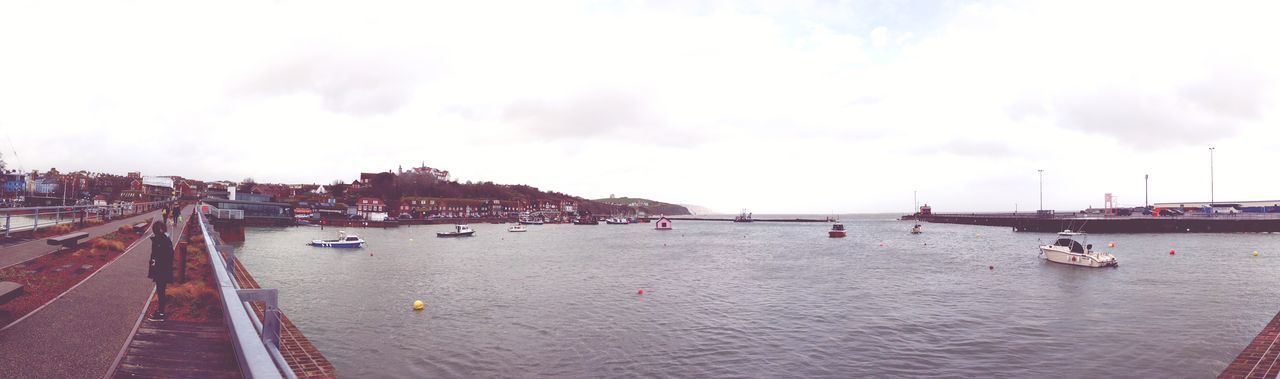 PANORAMIC VIEW OF PEOPLE BY RIVER AGAINST SKY