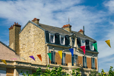 Low angle view of flags hanging on building against sky