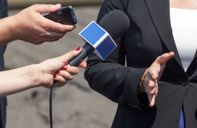 Cropped hand of female reporter holding microphone