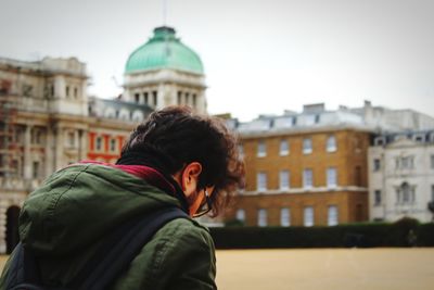 Rear view of man standing against building in city