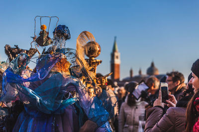Group of people photographing in city against clear sky
