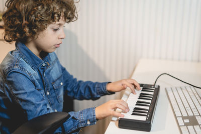 Cute boy playing piano at home