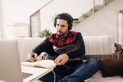 Young man using mobile phone while sitting on sofa at home