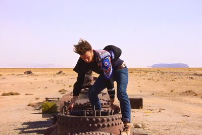 Man lifting metallic structure against clear sky