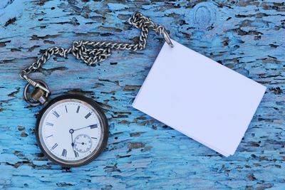 Close-up of clock with blank paper on table