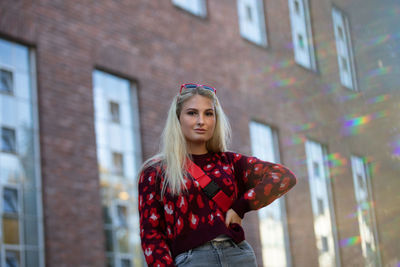 Portrait of young woman standing against red building