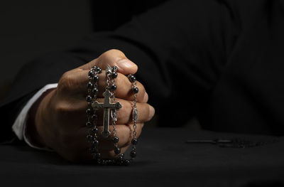 Close-up of hand holding cross against blurred background