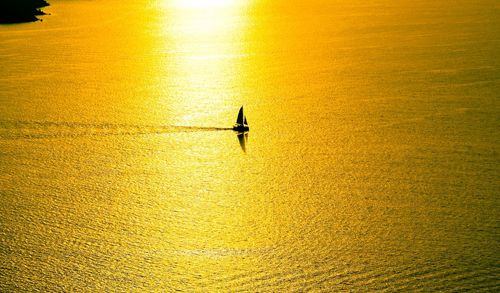 Silhouette sailboat sailing in sea during sunset