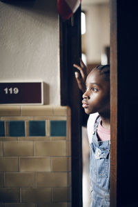 Thoughtful girl standing at doorway in school