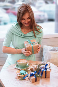Young smiling pregnant woman in cafe with cup of coffee and christmas gifts. pregnant lifestyle.