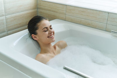 Young woman sitting in bathroom at home