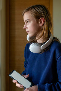 Portrait of a teen-ager with headphones holding mobile phone