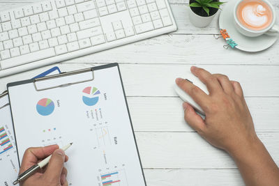 High angle view of hand using mobile phone on table