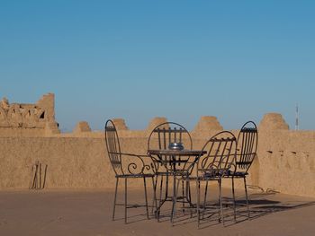 Empty chairs against clear blue sky