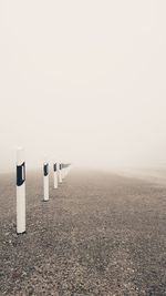 Bollards in row against sky during foggy weather