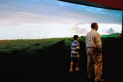 Rear view of men standing on land against sky