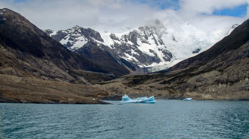 Scenic view of sea and snowcapped mountains against sky