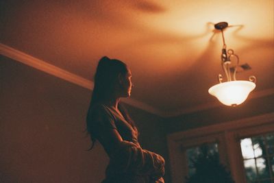 Low angle view of woman standing on illuminated ceiling