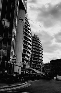 Road by buildings in city against sky