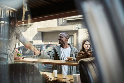 Male customer and salesman shaking hands at concession stand