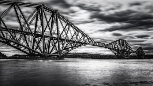 Bridge over river against cloudy sky