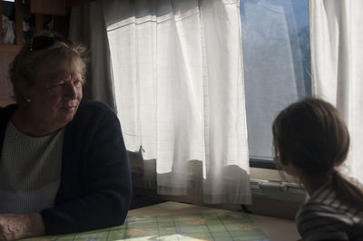 Side view of grandmother and daughter sitting by window in motor home