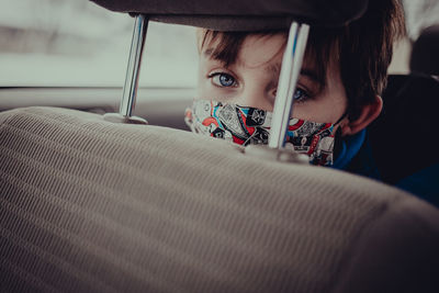 Young boy with mask on inside vehicle