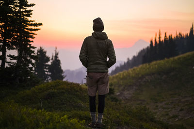 Rear view of man standing on field against sky