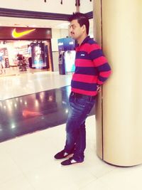 Side view of young man looking away while standing on tiled floor