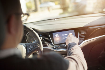 Man in car adjusting devices at home via smartphone