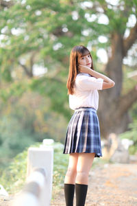 Portrait of young woman standing against trees