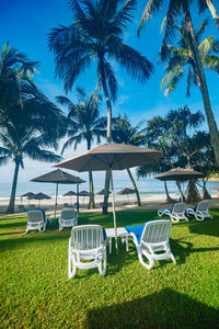 Lounge chairs by swimming pool at beach against sky