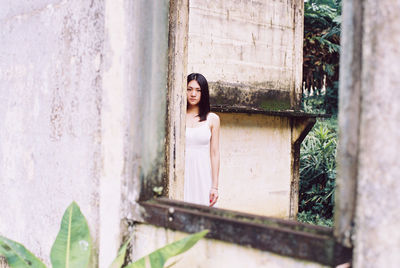 Portrait of young woman looking through window