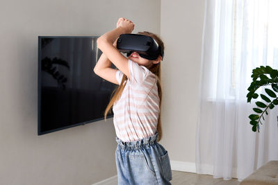 Full length of a boy holding camera at home