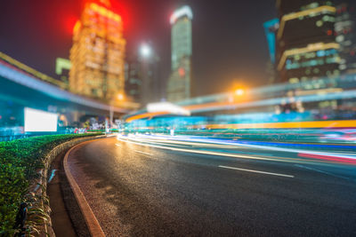 Light trails on street amidst buildings in city at night