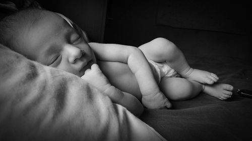 Close-up of cute baby lying on bed against black background