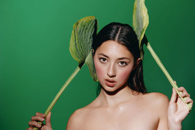 High angle view of shirtless young woman holding plant