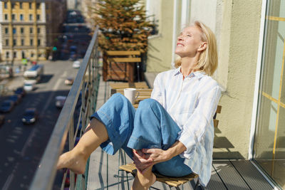 Young woman using mobile phone while sitting on chair