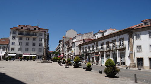 Street amidst buildings against clear blue sky