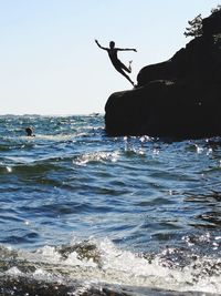 Silhouette people in sea against sky