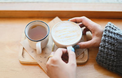 Midsection of woman holding coffee on table