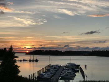 Boats moored in lake against sky during sunset