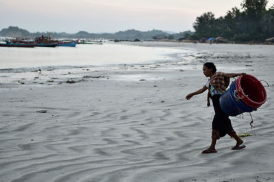 Side view of man on beach against sky