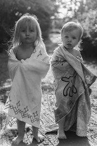 Portrait of siblings with towels standing at beach