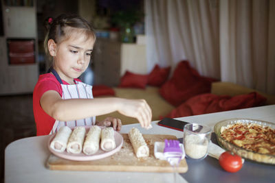 Cute boy preparing food on table at home